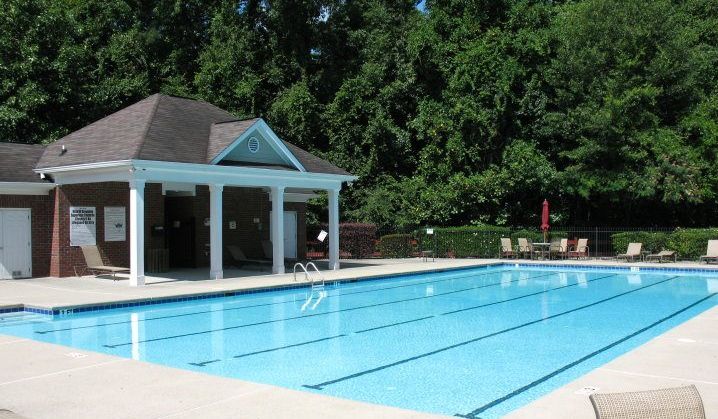 Lane-lined swimming pool beside a brick pool house with a covered porch